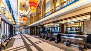A spacious lobby with a check-in counter, seating area, and a chandelier.