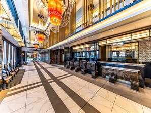 A spacious lobby with a check-in counter, seating area, and a chandelier.