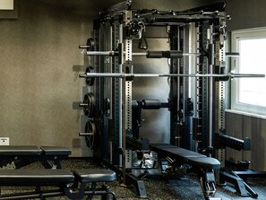 Un gimnasio con una estructura para sentadillas, banco de pesas y discos de pesas.