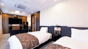 Habitación de hotel con dos camas, un escritorio, un televisor de pantalla plana, un minibar e iluminación empotrada en el techo.
