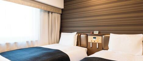 A hotel room with two beds, a wooden headboard, a control panel, and a window with curtains.
