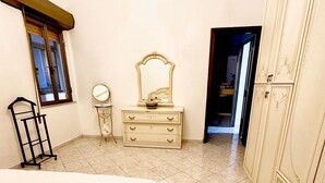 Een slaapkamer met een bed, een dressoir, een spiegel en een kledingkast.