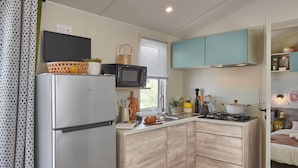 Una cocina compacta con refrigerador, microondas, estufa y gabinetes de madera.