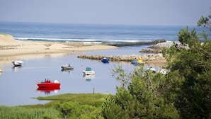 Escena costera con aguas tranquilas, barcos y una playa arenosa.