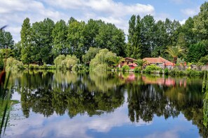 A tranquil lake with a gazebo and a small building surrounded by lush greenery. - Cottage PARKS LA COMTESSE - 3bed mobile home sleeps 6 (Bélus)