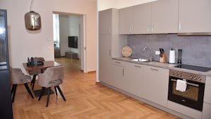 A modern kitchen with grey cabinets, a wooden dining table, and a built-in oven.