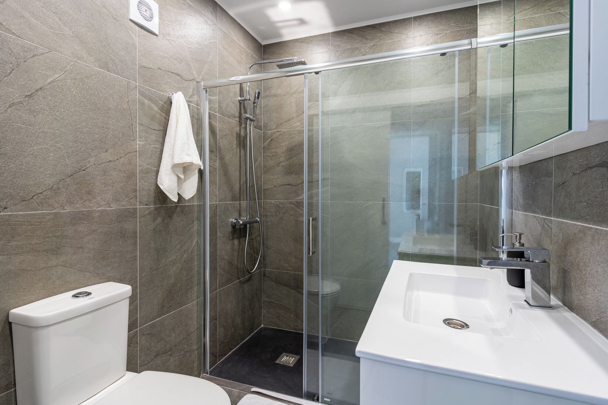 A modern bathroom with a glass shower enclosure, a white toilet, and a white sink.
