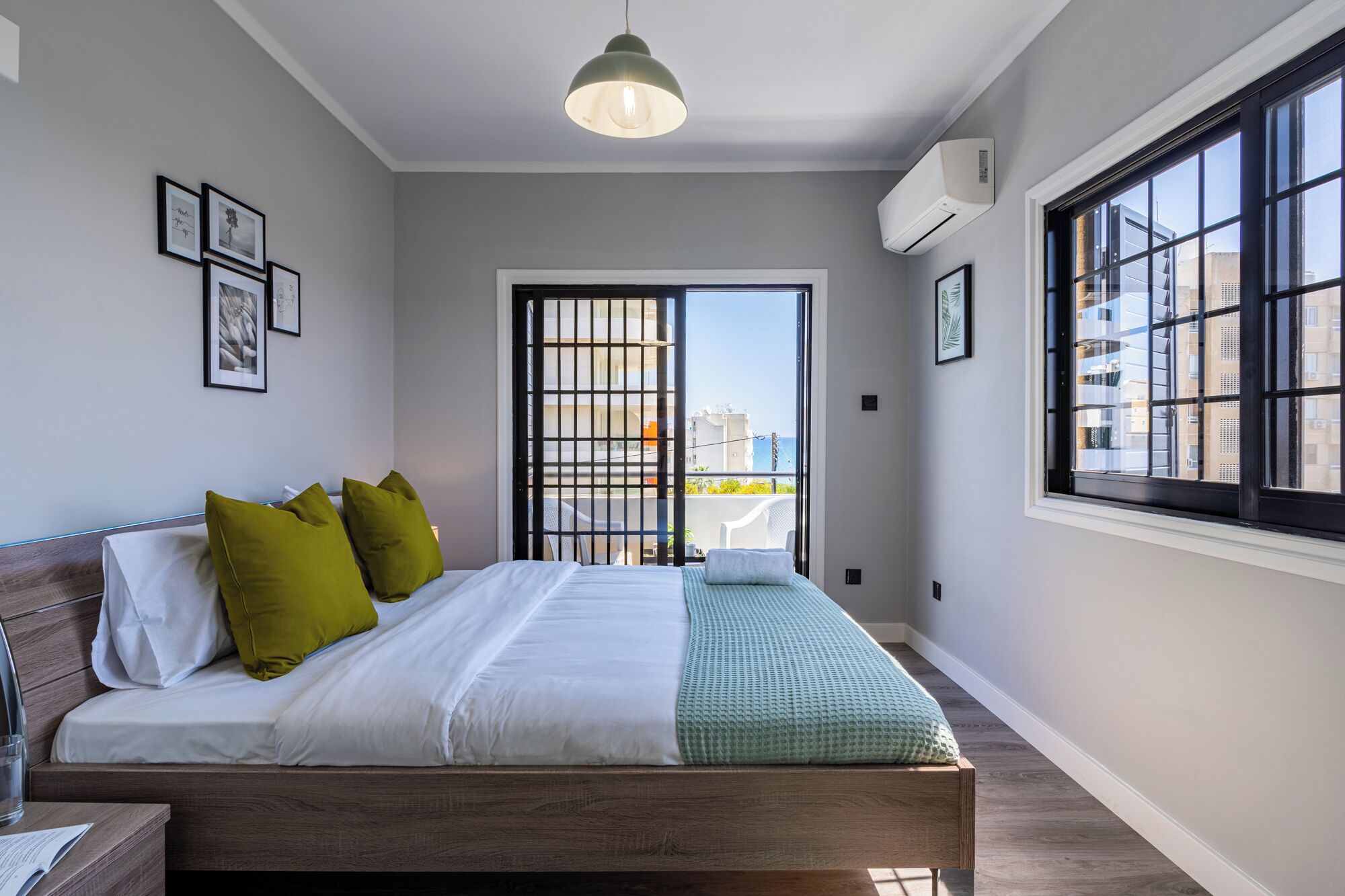 Un dormitorio moderno con cama, mesita de noche, ventana con vistas e iluminación en el techo.