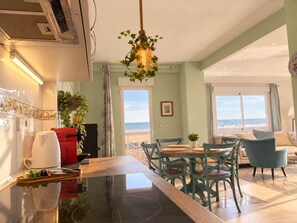 A modern kitchen with a central island, dining area with chairs, and a view to the outside. - Ninomad 02 Beachfront - Near Gandía (Daimús)