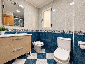 A bathroom with a checkered floor, a wooden vanity, a toilet, and a mirror. - Ninomad 02 Beachfront - Near Gandía (Daimús)