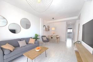 A modern living room with a sofa, coffee table, and dining area. - 04 Caerulea - Sea View Apartment - Daimús (Daimús)