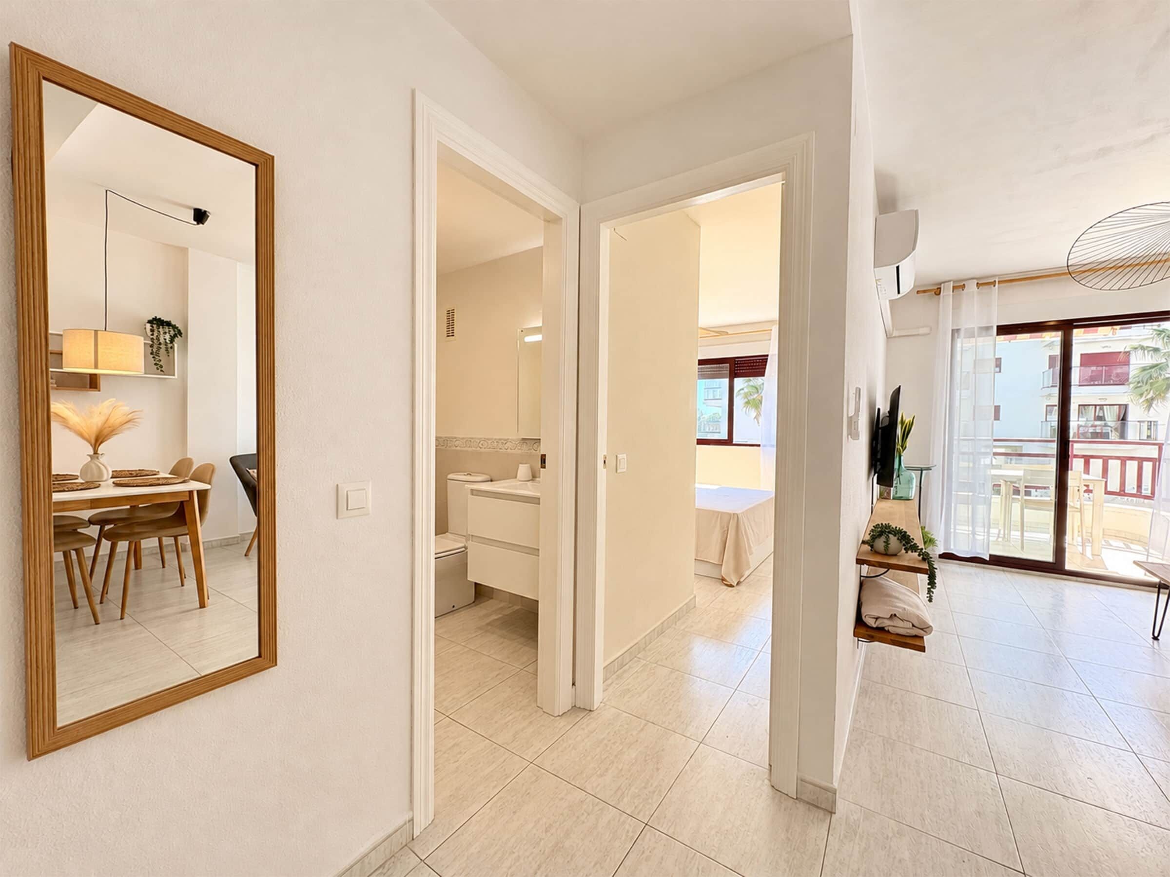 A modern interior with a dining area, a bathroom, and a balcony with a view.