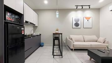 A modern kitchen with a built-in oven, a dining area with a sofa and a coffee table, and two abstract wall art pieces.