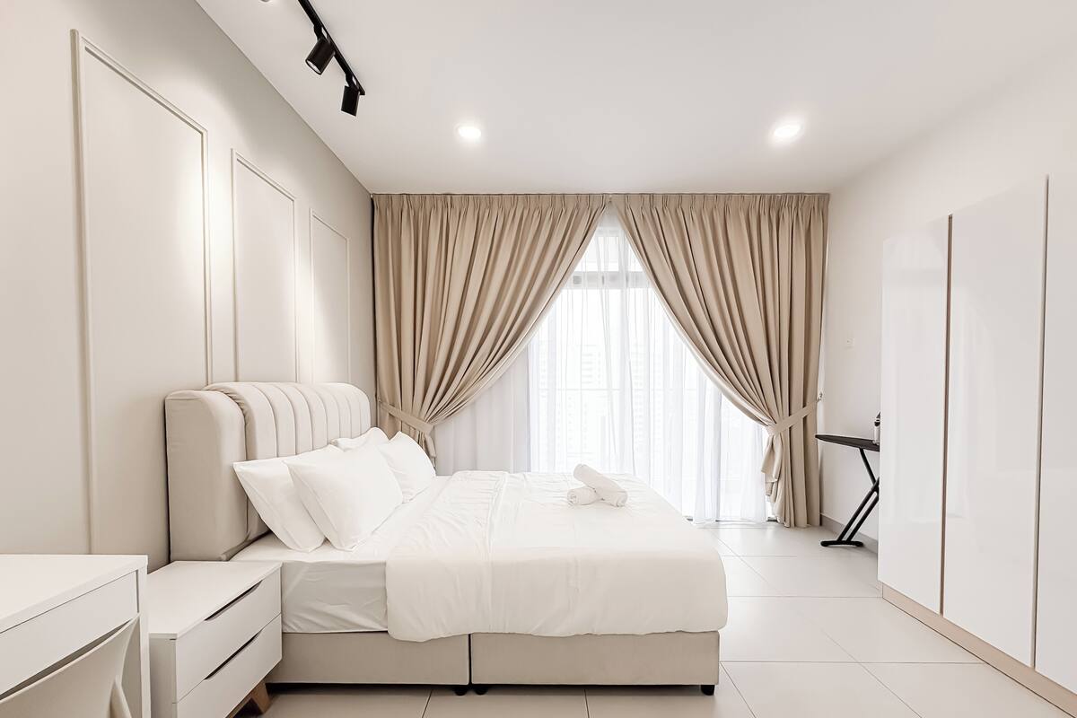 A modern bedroom with a bed, bedside tables, a desk, and a standing lamp.