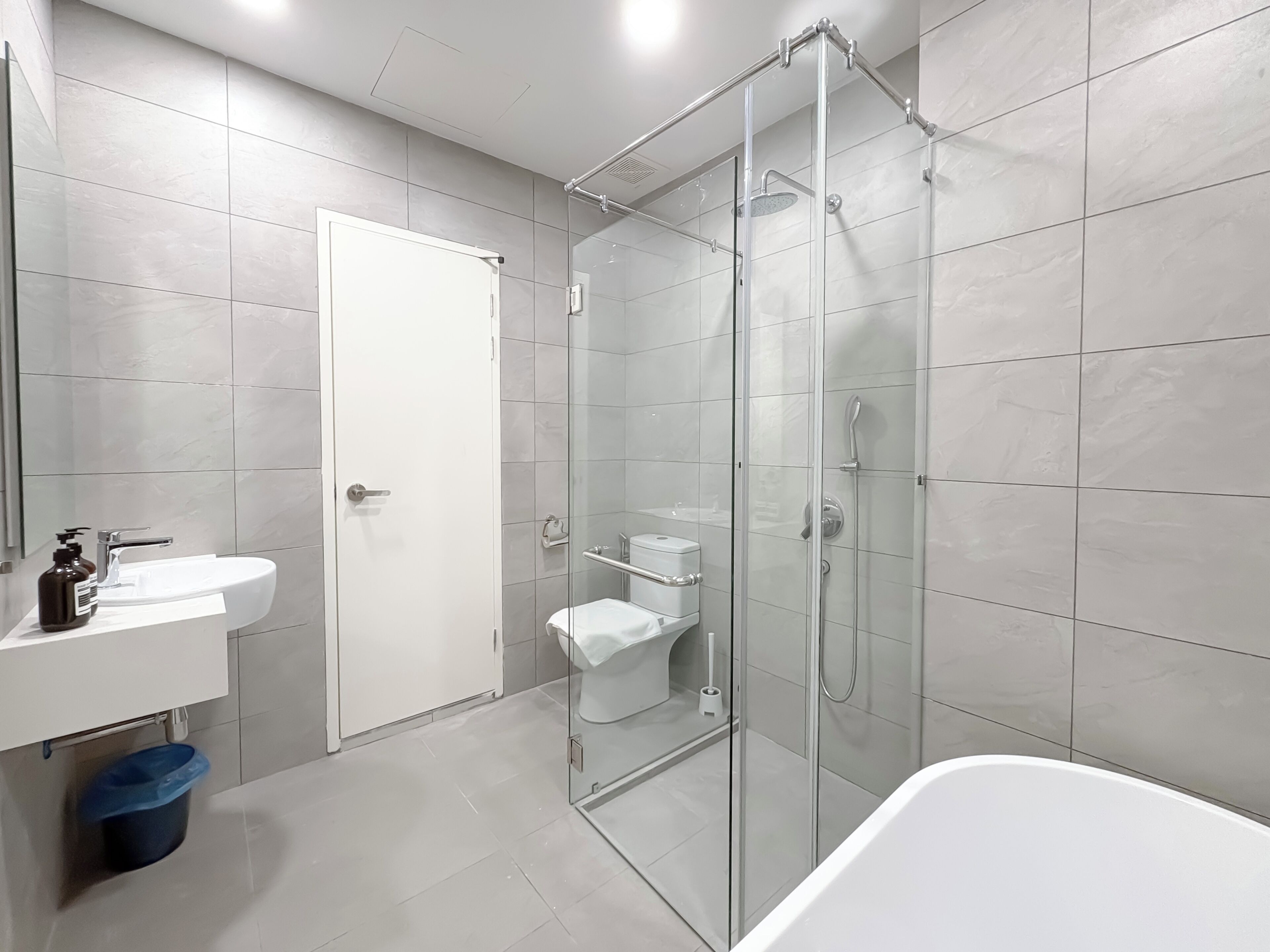 Un baño moderno con ducha de vidrio, lavamanos blanco y un inodoro.