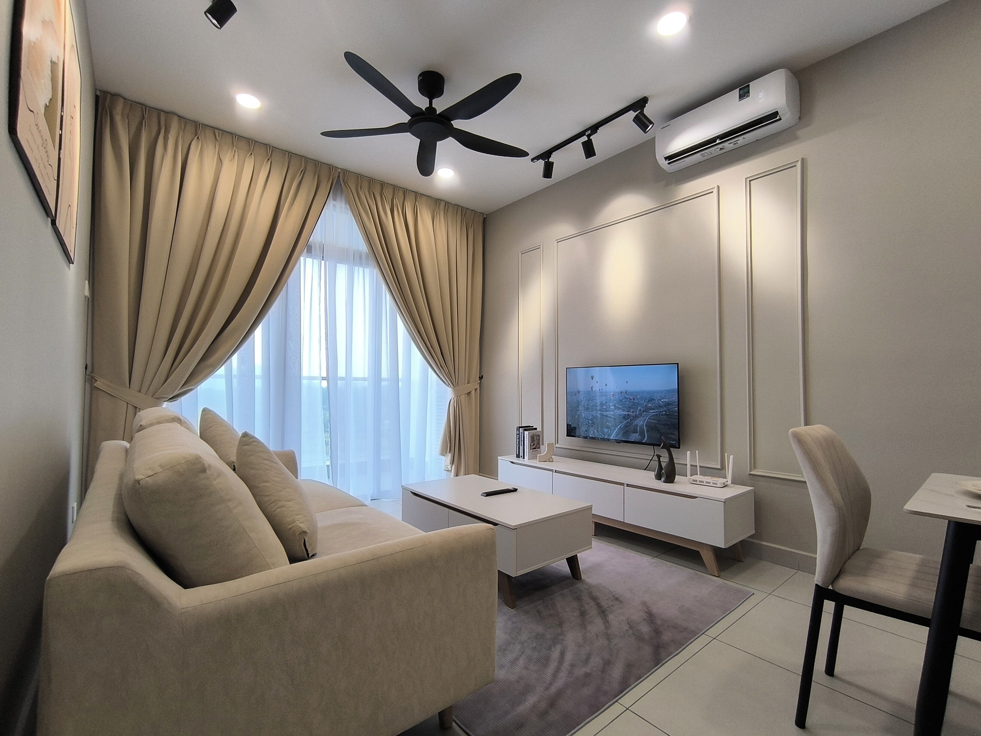 A modern living room with a sofa, a coffee table, a TV, and a ceiling fan.