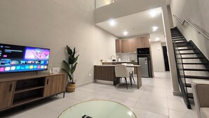 Een modern appartement met een woonkamer, keuken en eetgedeelte, voorzien van een flatscreen-tv, een potplant en een trap.