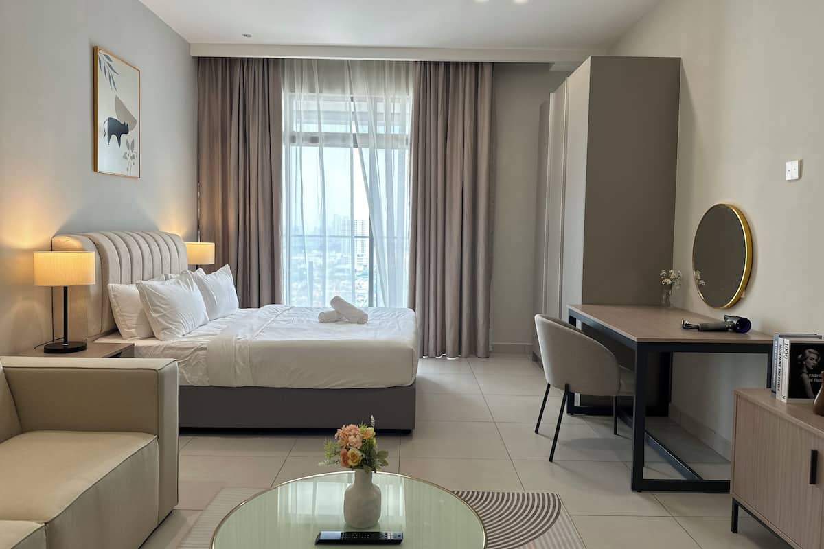 Une chambre dâhĂŽtel comprenant un lit, des lampes de chevet, un bureau, une chaise, une petite table basse ronde en verre et un vase avec des fleurs.