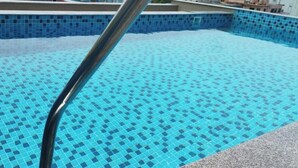 A swimming pool with a tiled edge and a metal handrail. - The Sea Valley Heights Puri (Puri)