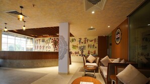 A hotel lobby with a reception desk, seating area, and decorative wall art. - The Sea Valley Heights Puri (Puri)