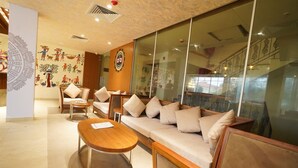 A modern hotel lobby with a sofa, chairs, a coffee table, and decorative wall art. - The Sea Valley Heights Puri (Puri)