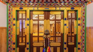 Una puerta tradicional con tallas intrincadas y diseños coloridos, flanqueada por dos columnas verticales con diseños similares.