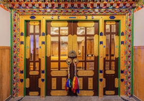 A traditional door with intricate carvings and colorful patterns, flanked by two vertical columns with similar designs.