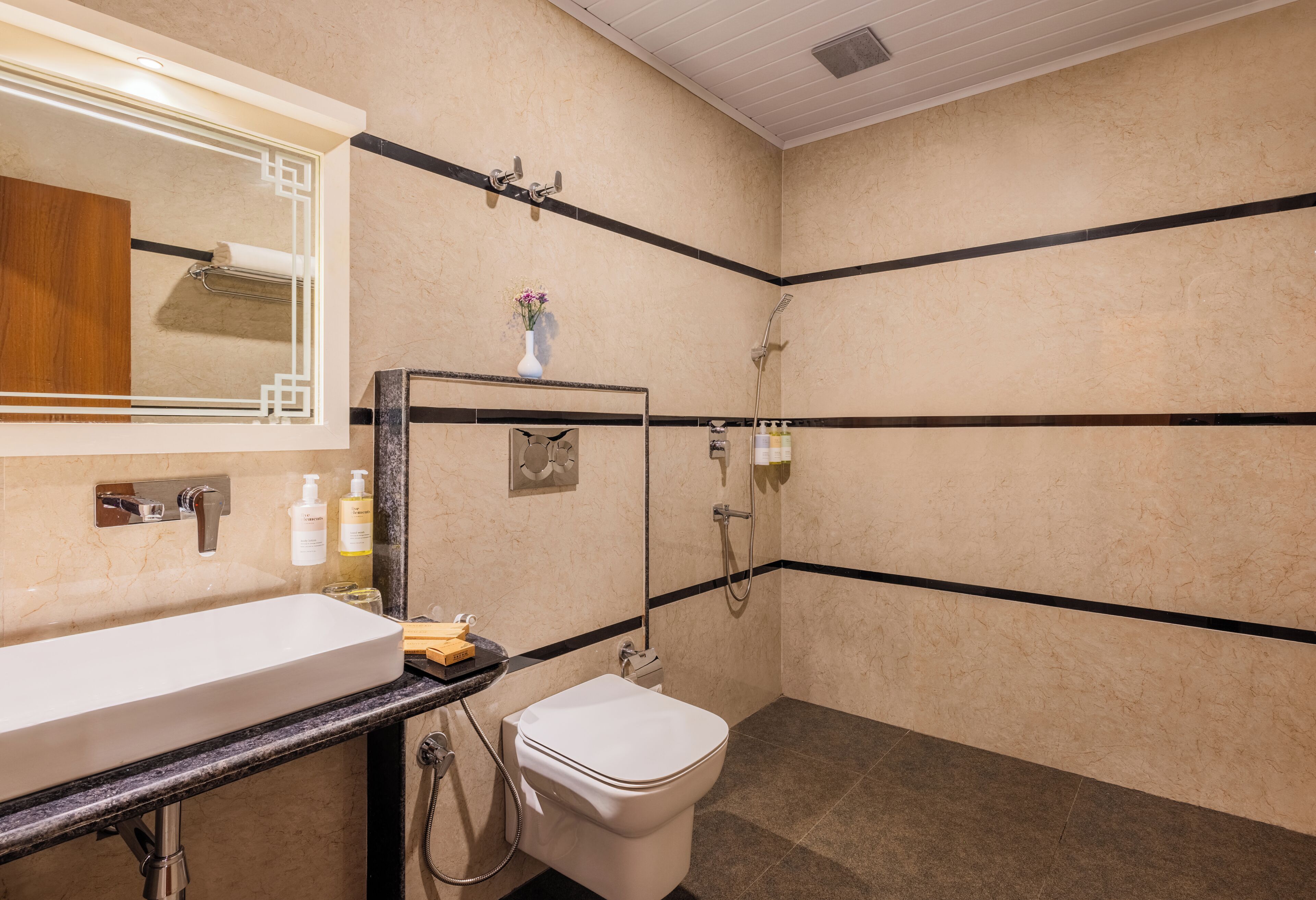 Ein Badezimmer mit weißem Waschbecken, Spiegel und Toilette, mit schwarzen Streifen an den Wänden und einem Duschbereich.
