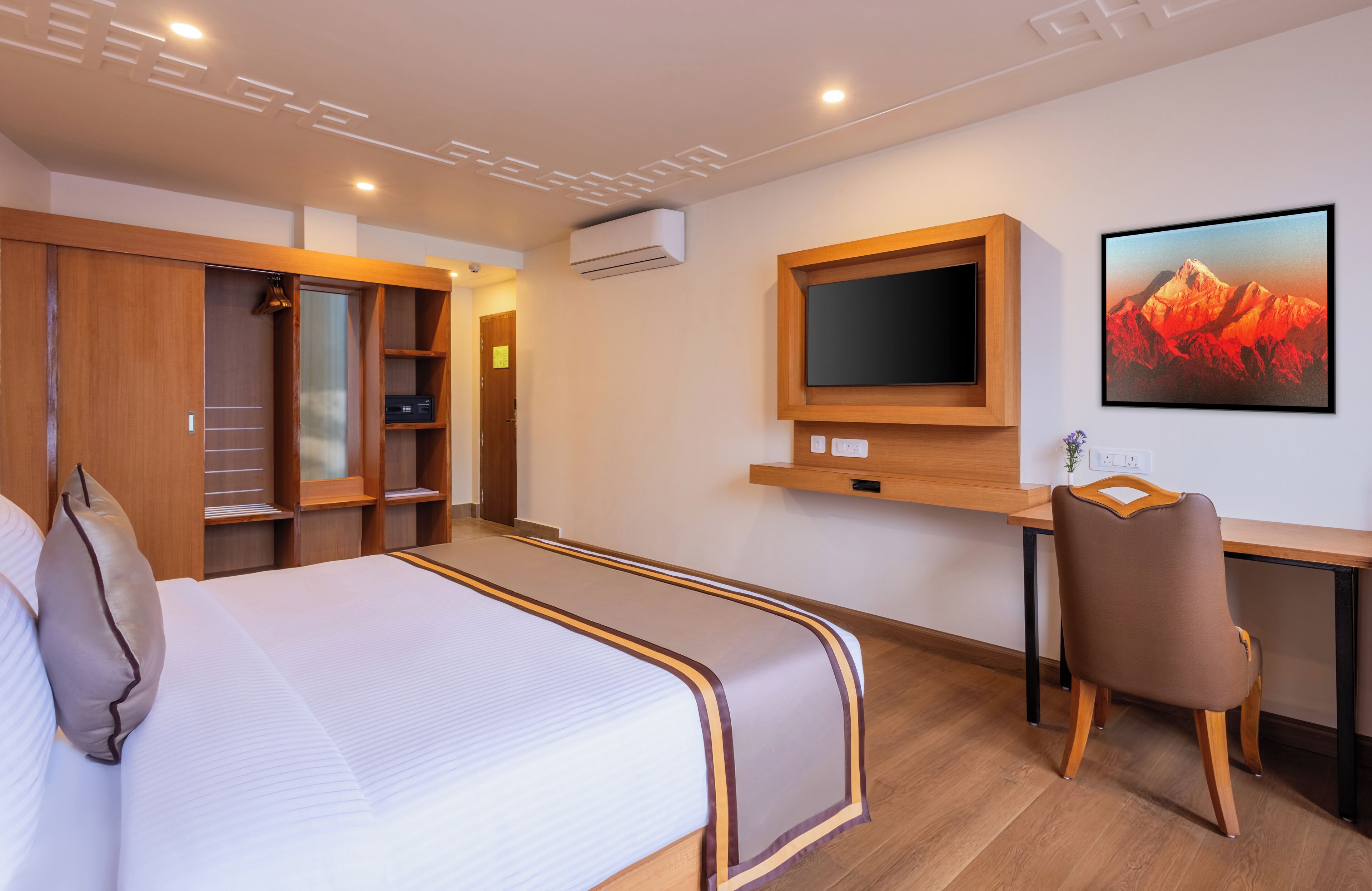 A hotel room with a bed, a desk, a chair, a TV, and a wardrobe.