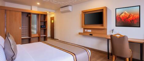 A hotel room with a bed, a desk, a chair, a TV, and a wardrobe.