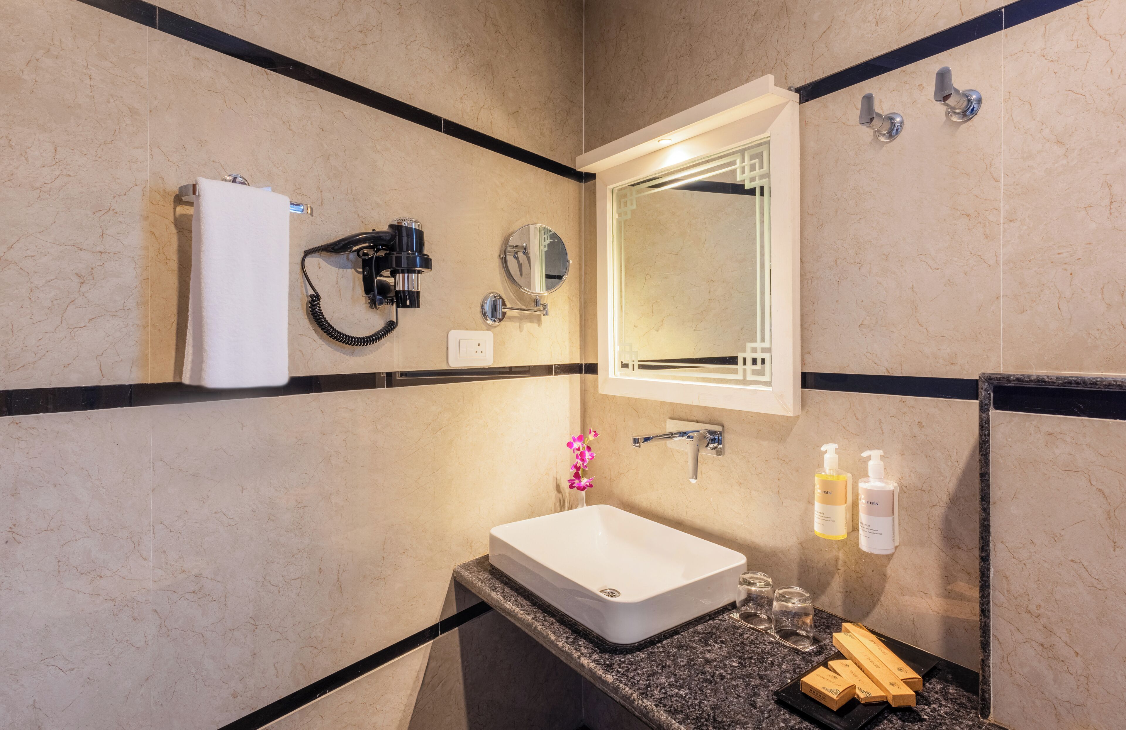 Een moderne badkamer met een witte wastafel, een spiegel, een handdoekhouder en toiletartikelen.