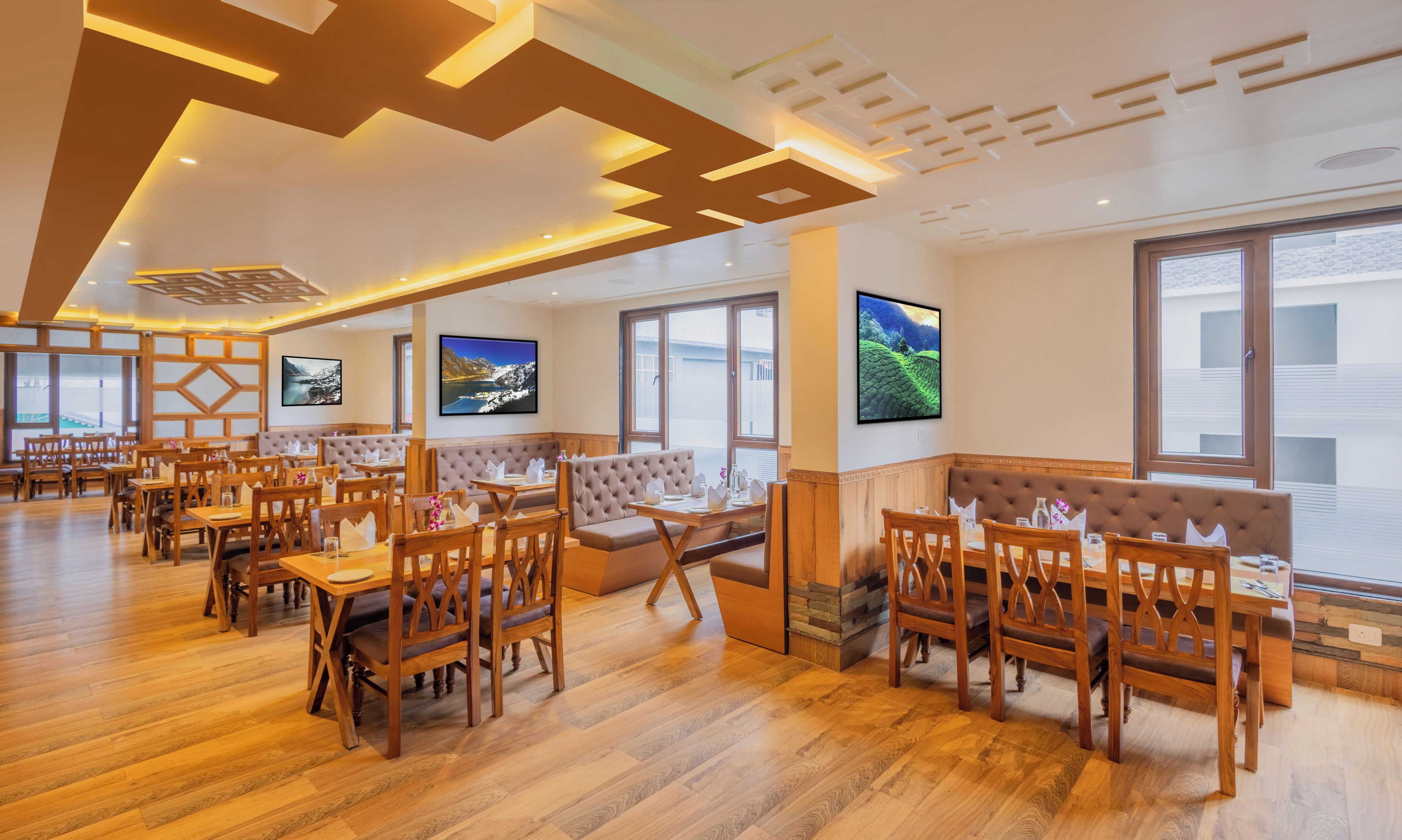 A restaurant with wooden furniture, large windows, and artwork on the walls.