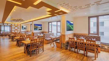 A restaurant with wooden furniture, large windows, and artwork on the walls.