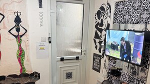 A room with a bed, a TV, a wall with decorative tiles, and a door with a frosted glass panel. - Cozy Guest Room Retreat in Scenic Kent Countryside (Kent)