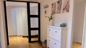A hallway with wooden flooring, a white cabinet with drawers, a wicker basket, and wall art.