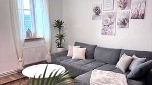 A modern living room with a grey sofa, a white coffee table, and a potted plant.