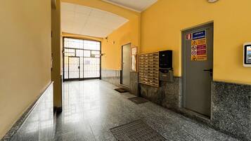 A hallway with a tiled floor, a door with a sign, and a mailbox.
