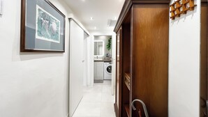 A hallway with a framed picture, a wooden door, and a glimpse of a kitchen area. - Sirtori Milano (Milan)