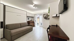 A modern living room with a sofa, a dining table, a kitchen area, and a balcony. - Sirtori Milano (Milan)
