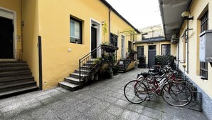 A narrow alleyway with a yellow building, a staircase, and a row of bicycles parked on the side. - Sirtori Milano (Milan)