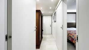 A narrow hallway with a wooden door, a white door, and a bed with a colorful quilt. - Sirtori Milano (Milan)