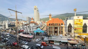 A busy urban street with a hotel, a clock tower, and various shops. - Cozy Ground Floor Suite with Shared Pool (Tambon Patong)