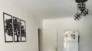 Un comedor con mesa de madera, banco, refrigerador y decoración en la pared.