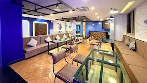 A modern interior with seating areas, tables, and a reception desk. - Modern Ground Floor Suite with Shared Pool (Tambon Patong)