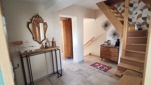A hallway with a wooden staircase, a console table with a mirror, a small stool, and a wooden dresser. - Provençal villa, swimming pool and wooded garden in a quiet location (Vence)