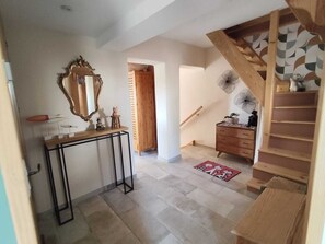 A hallway with a wooden staircase, a console table with a mirror, a small stool, and a wooden dresser. - Provençal villa, swimming pool and wooded garden in a quiet location (Vence)