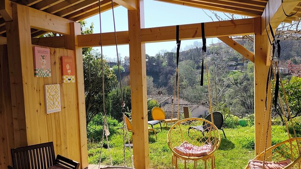 A wooden deck with a bench, a hanging chair, and a swing chair. - Provençal villa, swimming pool and wooded garden in a quiet location (Vence)