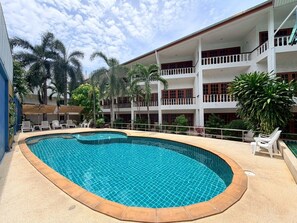 Un hotel con piscina, varios balcones y palmeras.