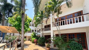 A courtyard with a tiled walkway, palm trees, potted plants, and outdoor seating. - Serene Suite with Balcony and Pool View (Tambon Patong)