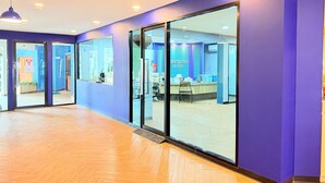 A hotel reception area with a reception desk, glass doors, and a blue wall. - Serene Suite with Balcony and Pool View (Tambon Patong)